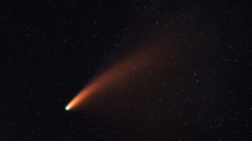 un segno rosso di cometa su un cielo stellato nero