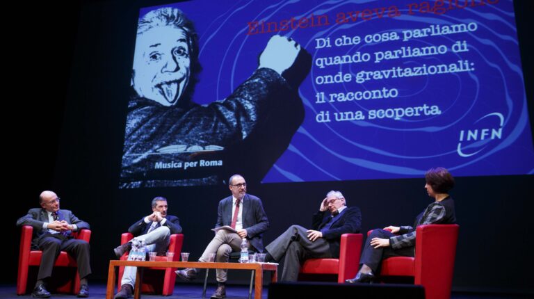 Sul palco, da destra, i fisici Viviana Fafone e Fulvio Ricci, il giornalista Marco Cattaneo, i fisici Fernando Ferroni e Antonio Masiero. Sullo sfondo, immagine di Einstein sovrapposta a rendering delle onde gravitazionali generale da due stelle di neutroni