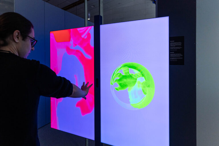 Installazione sul dualismo onda particella. Due schermi mostrano l'immagine del visitatore o della visitatrice in forma di onda o di particella. Foto di Matteo de Stefano.